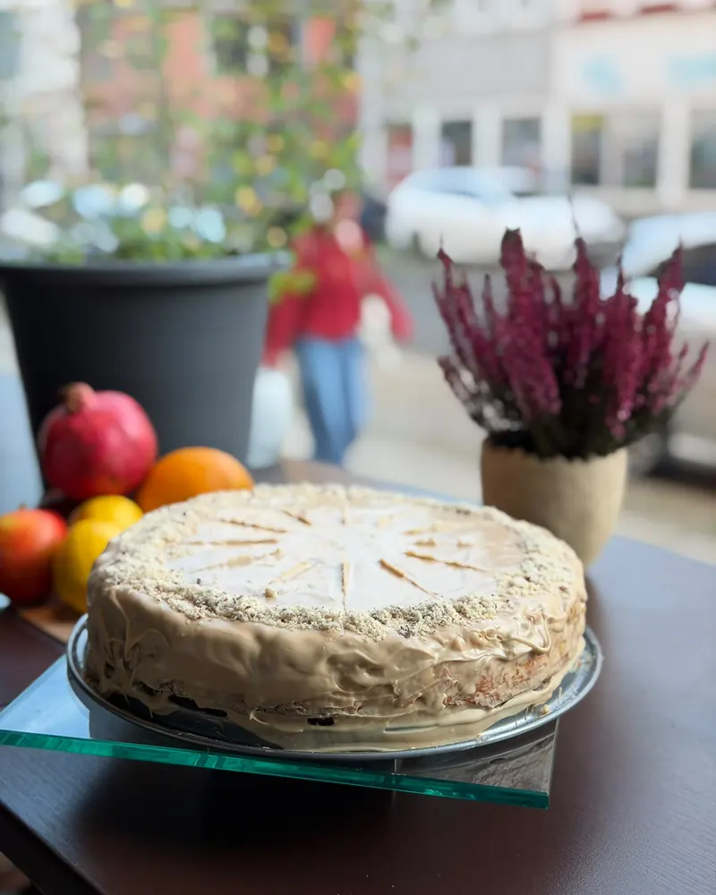Ein Kuchen der Woche mit hellbrauner Creme am Fenster, daneben Heidekraut im Topf