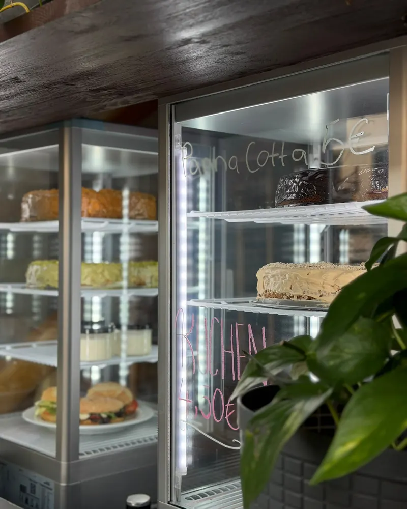 Beleuchtete Kuchenvitrine, auf der Scheibe steht „Panna Cotta 5 €“